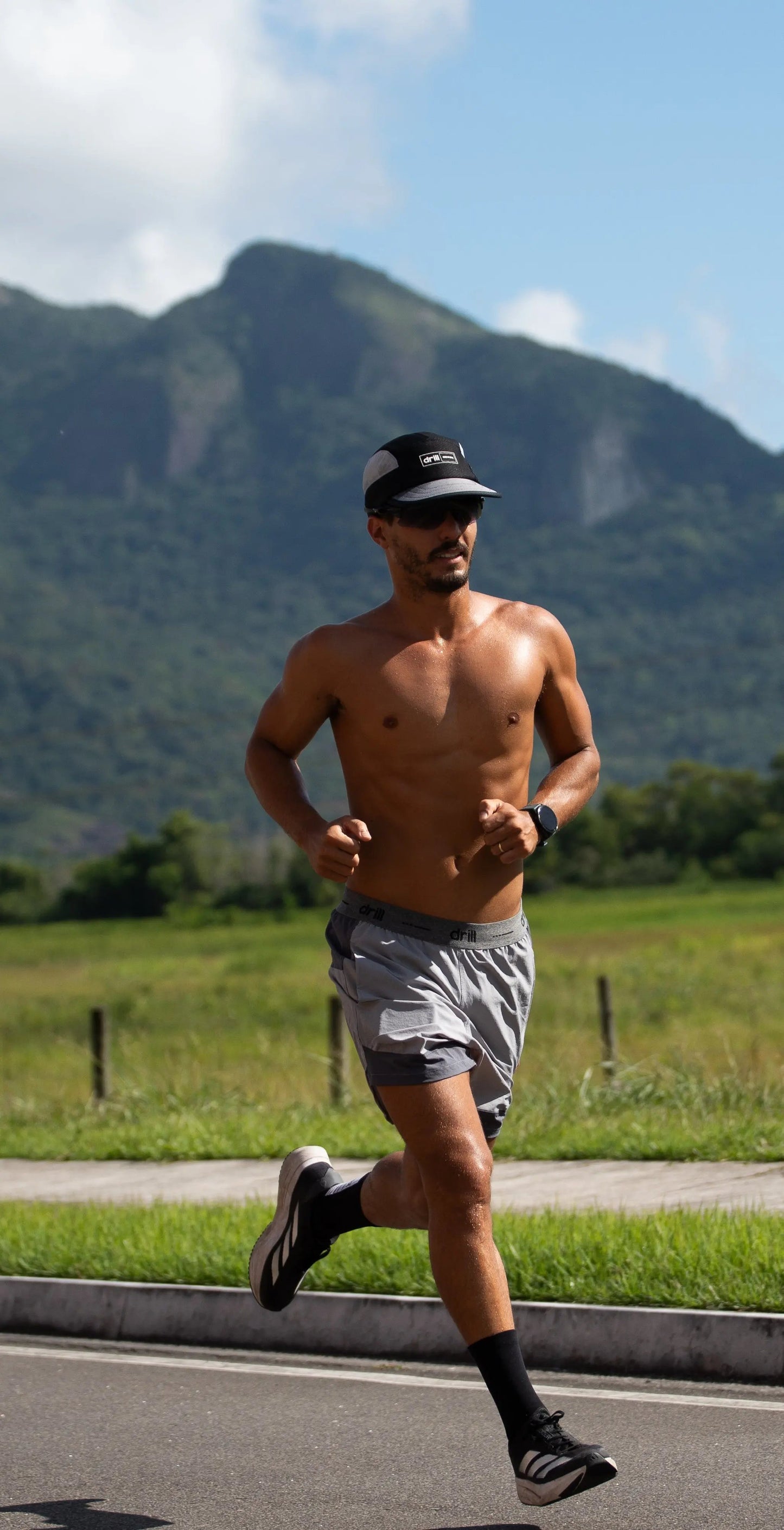 Homem correndo com short cougar masculino yvy em cenário montanhoso, mostrando conforto e liberdade de movimento.